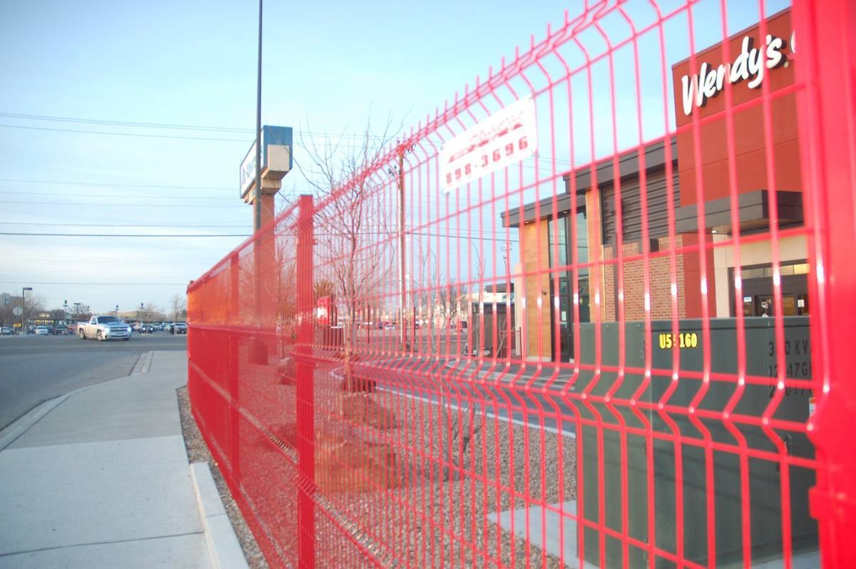 Red welded-wire security fence installed along a commercial property