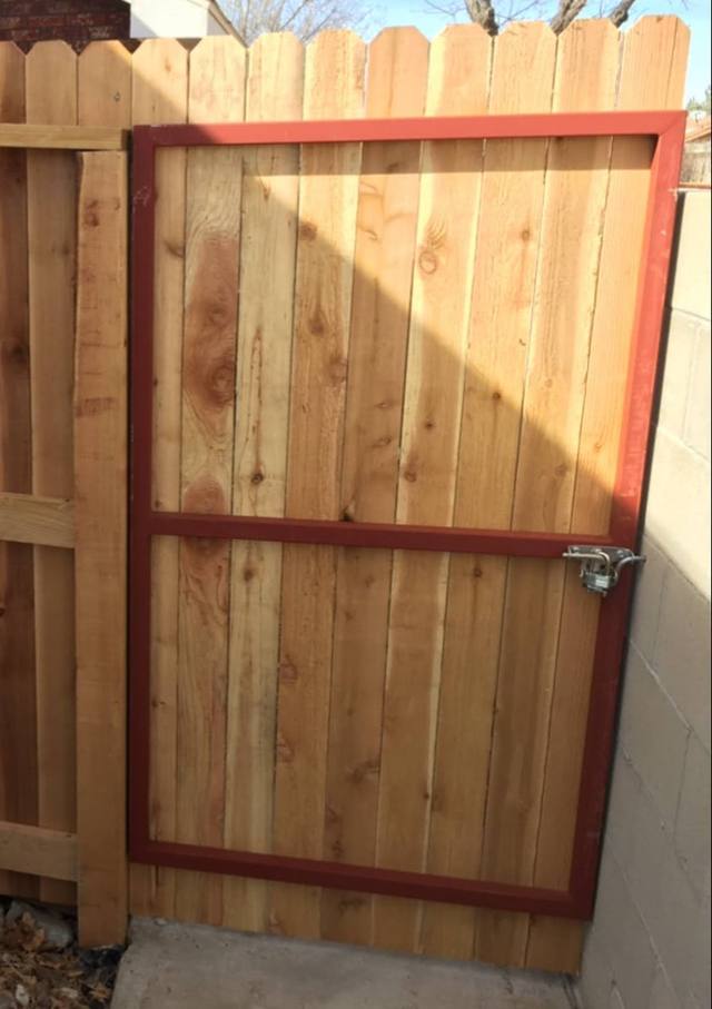 Wooden gate with red frame in a wooden fence.